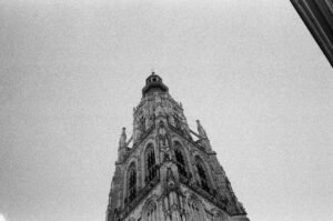 Low angle black and white photo of the Grote Kerk tower in Breda, Netherlands.