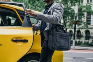 Side view of crop anonymous African American male opening door of bright yellow cab on street